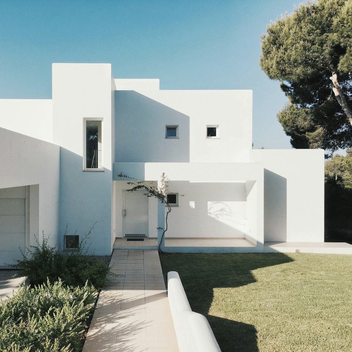 property white concrete house near green tree during daytime